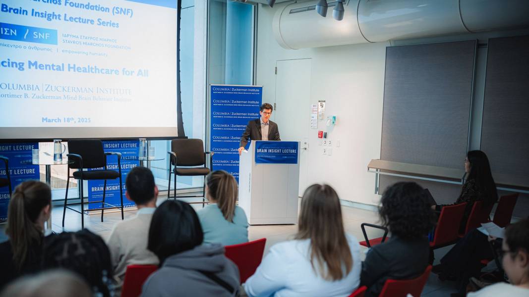 A speaker stands on a podium giving an SNF Brain insight lecture at Columbia’s Zuckerman Institute